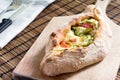 Peinirli with gouda cheese, tomato and green peppers on wooden cutting board. Knife and fork on kitchen towel