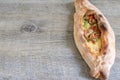 Peinirli - Greek open faced pizza with ham, cheese and vegetables on wooden kitchen surface with copy space