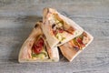 Peinirli - Greek open faced pizza with ham, cheese and vegetables, three half pieces on wooden kitchen surface Royalty Free Stock Photo