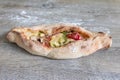 Peinirli - Greek open faced pizza out of the oven on wooden kitchen surface