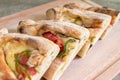 Peinirli - Greek open faced pizzas with ham, cheese and vegetables, cut in halves and stacked on wood cutting board