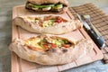 Peinirli - Greek open faced pizzas together with vegetarian sandwich on wood cutting board. Knife and fork on the side