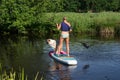 Peize, Netherlands July 16, 2021: A tanned woman in a t-shirt with bikini bottoms on a sup board. With an Australian