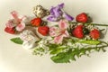 Flowers of pink and white Alstroemeria and branches of purple iris on white plywood