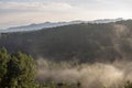 pemandangan kabut melintasi bukit pegunungan di pagi hari