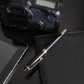 Pen, agenda, camera and a tablet on a black table with copy space for your text Royalty Free Stock Photo