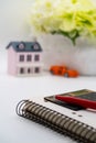 Pen and calculator lie on a blank page of a notebook against the background of flowers, a toy house and a car, dreams, mood Royalty Free Stock Photo