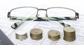 Pen on financial and accounting reports with coins stacks, glasses and calculator