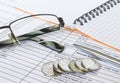 Pen on financial and accounting reports with coins stacks, glasses and calculator in background