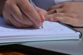 Pen in hand, woman writing in a spiral bound notebook