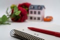 The pen lies on a blank page of the weekly journal against the background of flowers, a toy house and a car, dreams, mood Royalty Free Stock Photo