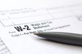 The pen lies on the tax form W-2 Wage and Tax Statement. The tim