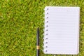 Pen on note book on grass background.