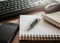 Pen on notebook with computer keyboard, mouse and cell phone Royalty Free Stock Photo