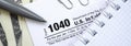 The pen, notebook and dollar bills is lies on the tax form 1040