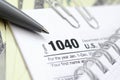 The pen, notebook and dollar bills is lies on the tax form 1040 U.S. Individual Income Tax Return. The time to pay taxes