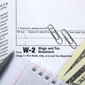 The pen, notebook and dollar bills is lies on the tax form W-2 W