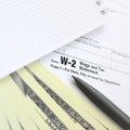 The pen, notebook and dollar bills is lies on the tax form W-2 W