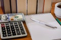 Pen with notepad, dollars and calculator on the background of books Royalty Free Stock Photo