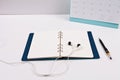A pen is placed on a diary of blank notes, against the background.