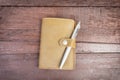 Pen on top of yellow organizer with leather cover on wooden background. Royalty Free Stock Photo