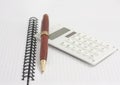 Pen and white calculator on the spiral notepad