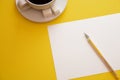 Pen white paper and coffee Cup on yellow background with copy space top view