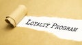 Pen and white torn paper strip on a brown background with the text LOYALTY PROGRAM