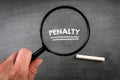 PENALTY. Text, magnifying glass and white chalk on a blackboard