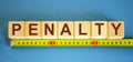 `Penalty` word on cubes arranged behind the ruler on blue background. Business concept