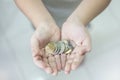 Penang, Malaysia - January 14, 2020 : Closed up of small asian boy hand holding handful of Malaysia coins.Concept of saving and