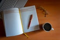 Pencil on a blank journal with reading glasses, cup of coffee and laptop next to it Royalty Free Stock Photo