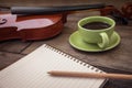 Pencil on book and coffee cup with violin on wooden table