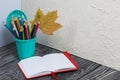 A pencil case in the form of a trash can. It contains colored pencils. Nearby is a notebook for notes. Dried maple leaves are Royalty Free Stock Photo