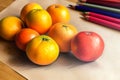 A pencil drawing mandarins and an apple on a piece of paper near pencils. Created with Generative AI