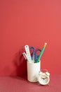 Pencil holder with ruler, scissors, pen and alarm clock on red desk. red wall background, workspace Royalty Free Stock Photo