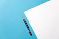 Pencil lies on a paper sheet on blue background, top view. Office space creativity minimalism concept