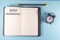 Pencil, notebook with 2020 resolutions and alarm clock