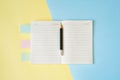 Pencil on opened note book with pastel blue and yellow paper background