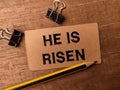Pencil and paper clips with the word HE IS RISEN Royalty Free Stock Photo