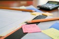 pencil and paper on a desk with sticky notes and a calculator beside Royalty Free Stock Photo