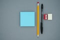 Pencil, pen, scraper, eraser and blue blank sticky notes, on a gray background, top view. School office supplies Royalty Free Stock Photo