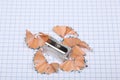 Pencil sharpener and pencil shaving rest on a squares sheet Royalty Free Stock Photo