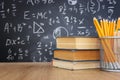 Pencils and books infront of blackboard with formulas. education concept Royalty Free Stock Photo