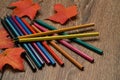 Pencils of different colors and autumn leaves on the table Royalty Free Stock Photo