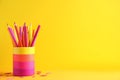 Pencils with felt pens in holder and paper clips on yellow background Royalty Free Stock Photo