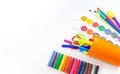 Pencils and felt-tip pens in a plastic cup, paints and pastel crayons on a white background Royalty Free Stock Photo