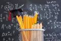 Pencils and graduation hat infront of blackboard with formulas Royalty Free Stock Photo