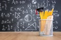 Pencils and graduation hat infront of blackboard with formulas. education concept Royalty Free Stock Photo