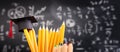 Pencils and graduation hat infront of blackboard with formulas. education concept Royalty Free Stock Photo